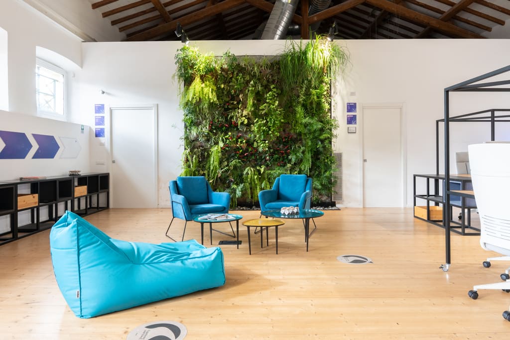 La sala principale della Digital Farm con la parete verde, l’area lounge e il parquet