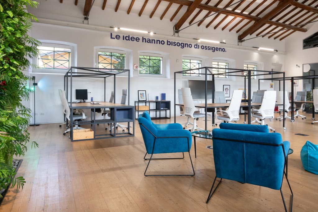 Area lounge con poltrone blu sotto le capriate della sala principale